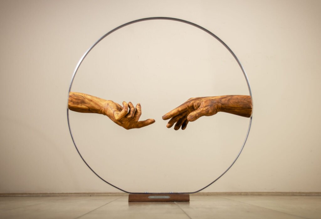 Sculpture en bois contemporaine représentant les mains inspirées de la Création d’Adam de Michel-Ange